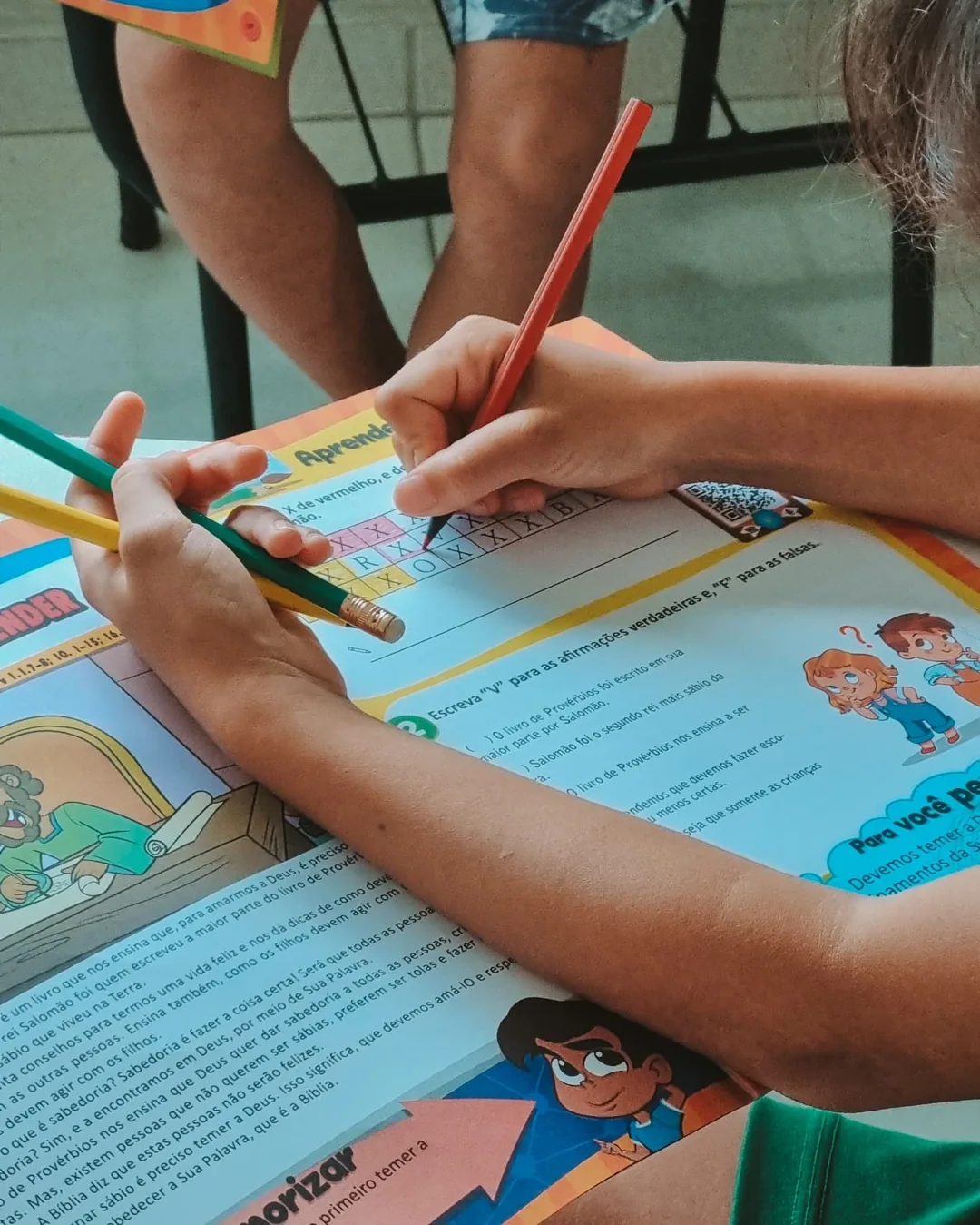 A child's hands completing, with colored pencils, a Bible activity on the book of Proverbs