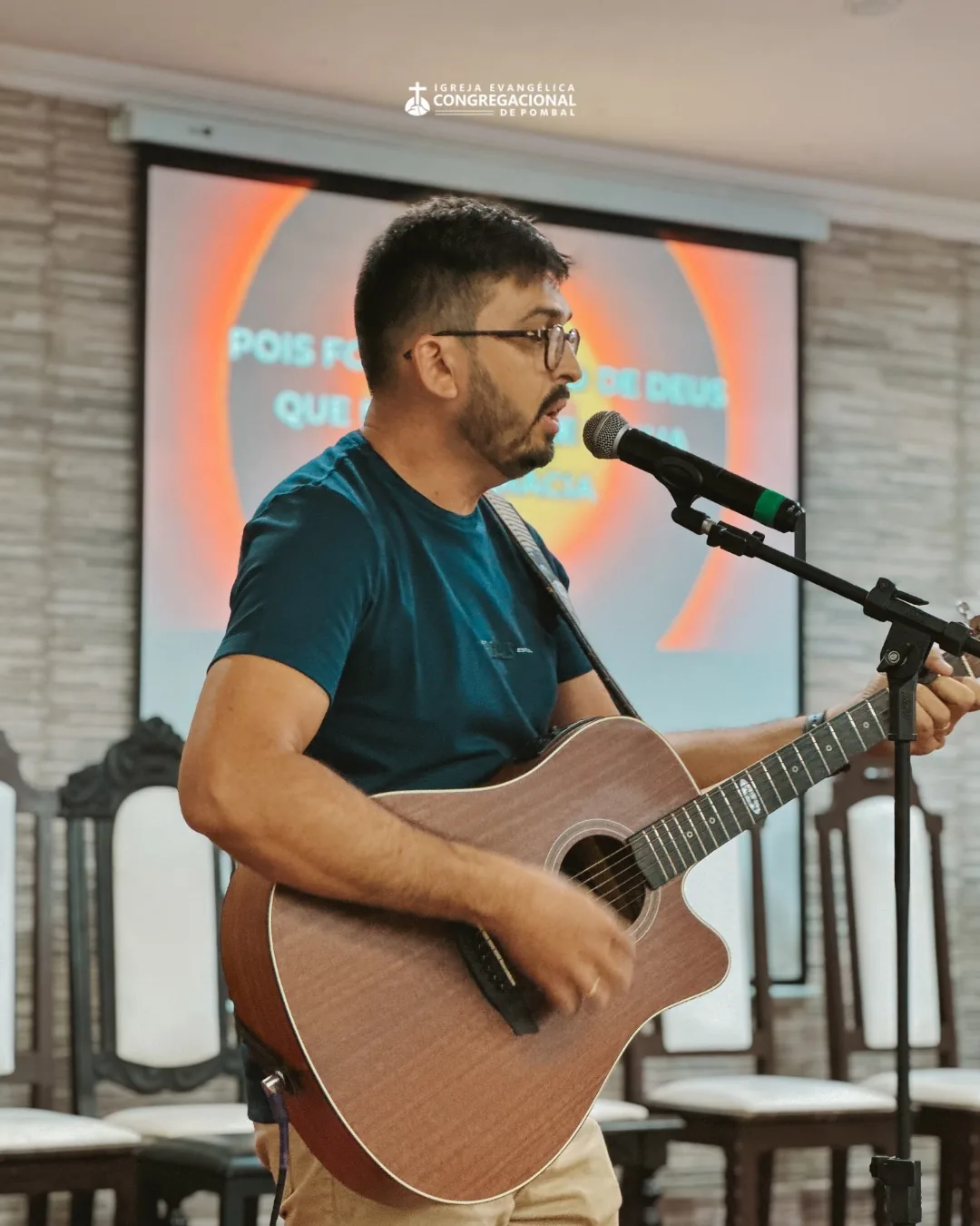 Guitarist leading the singing, with the lyrics projected in the background