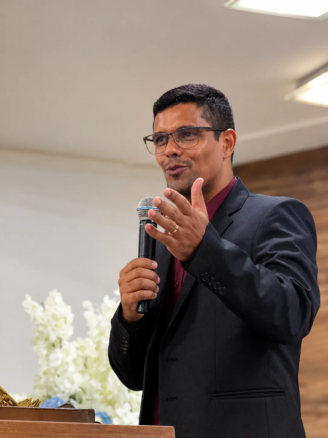 Pastor Felipe Oliveira preaching from the church pulpit, microphone in hand